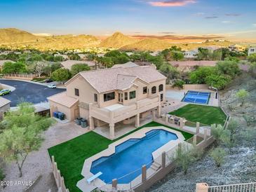 Expansive home with private pool, diving board, and tennis court nestled against a mountain backdrop at sunset at 14049 S 8Th St, Phoenix, AZ 85048