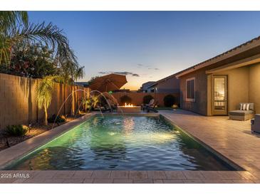 Inviting backyard oasis featuring a sparkling pool, fountain features, and relaxing seating areas perfect for outdoor entertaining at 21283 E Camacho Rd, Queen Creek, AZ 85142