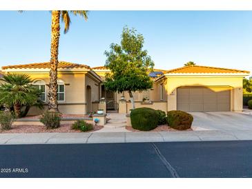 Inviting home featuring a meticulously manicured front yard and a covered two-car garage at 23213 N Del Monte Dr, Sun City West, AZ 85375