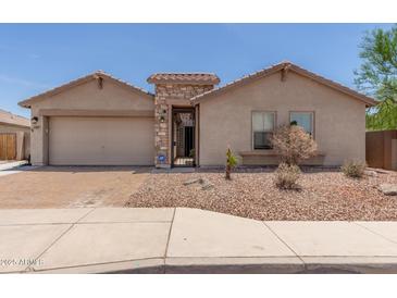 Charming single-story home with a brick-paved driveway and beautiful desert landscaping at 25667 W Primrose Ln, Buckeye, AZ 85326