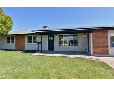 Charming single-story home with a well-maintained front lawn, solar panels, and stylish exterior accents at 3310 W Sweetwater Ave, Phoenix, AZ 85029
