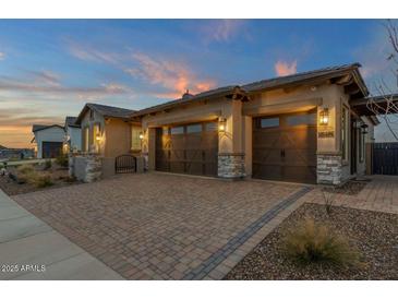 Charming home with a spacious three-car garage and a beautiful brick driveway at sunset at 5756 E Star Valley St, Mesa, AZ 85215