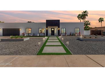 Modern exterior showcasing a sleek design with a dark garage door and a stone pathway at 6539 E Sharon Dr, Scottsdale, AZ 85254