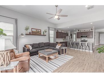 Open-concept living room featuring modern furnishings and an adjacent kitchen with stainless steel appliances at 681 W Belmont Red Trl, San Tan Valley, AZ 85143