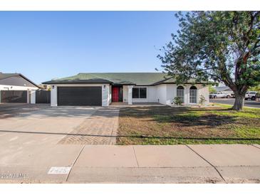 Charming single-story home with a well-maintained front yard, a black garage door, and a red front door at 7425 W Corrine Dr, Peoria, AZ 85381
