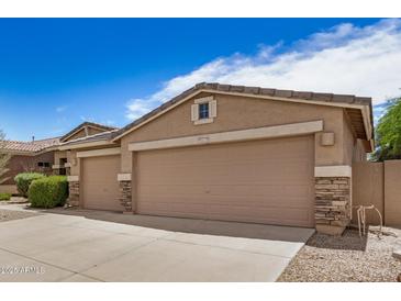 Home's charming exterior featuring a spacious three-car garage with stone accents and a well-maintained driveway at 17773 W Manso St, Goodyear, AZ 85338
