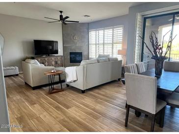 Spacious living room featuring a fireplace, ceiling fan, and dining area with lots of natural light at 19550 N Grayhawk Dr # 2023, Scottsdale, AZ 85255