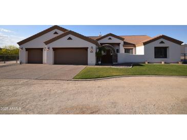 Charming single story home featuring a three car garage, manicured lawn and desert landscaping at 19880 W Desert Views Dr, Casa Grande, AZ 85122