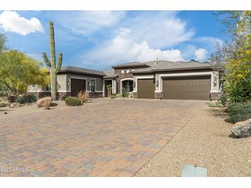 Charming home featuring a brick driveway, lush desert landscaping, and a three-car garage at 35971 N Prickley Pear Rd, Cave Creek, AZ 85331