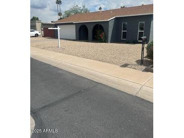 Charming single-story home featuring an attached garage, arched entryway, and desert-friendly landscaping at 5211 W Beryl Ave, Glendale, AZ 85302