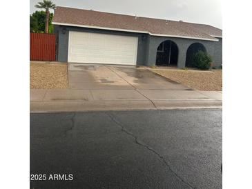 Single story home featuring a white garage door, an archway entrance and low maintenance desert landscaping at 5211 W Beryl Ave, Glendale, AZ 85302