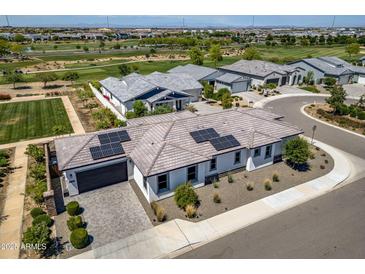 Stunning aerial view of a community featuring a home with solar panels, lush golf course and scenic surroundings at 17376 W Wildwood St, Surprise, AZ 85388