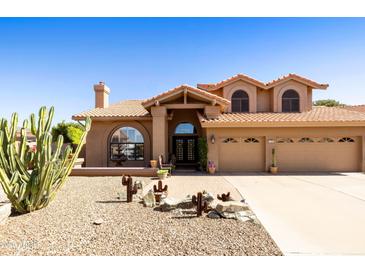 Inviting home featuring desert landscaping, a tile roof, arched windows and a three car garage at 3538 E Squawbush Pl, Phoenix, AZ 85044