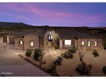 Stunning home exterior showcases desert landscaping, stone accents, and a tile roof under a vibrant sunset sky at 9936 E Winter Sun Dr, Scottsdale, AZ 85262