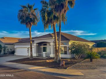Charming single-Gathering home with well-maintained landscaping and mature palm trees against a bright blue sky at 16398 N Oachs Dr, Surprise, AZ 85374