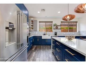 Bright kitchen boasts blue lower cabinets, stainless steel appliances, and a farmhouse sink at 20713 N 91St Dr, Peoria, AZ 85382