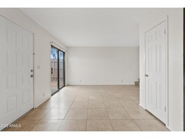 Bright living room featuring neutral tile flooring and sliding glass door to patio at 286 W Palomino Dr # 103, Chandler, AZ 85225