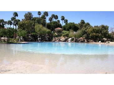 Lagoon-style community pool with sandy beach entry and lush landscaping at 1633 E Lakeside Dr # 143, Gilbert, AZ 85234