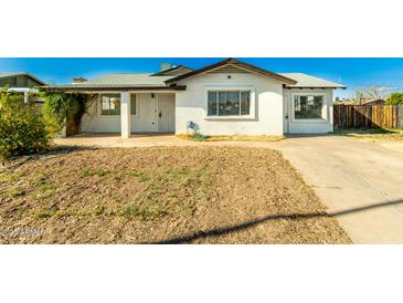 Charming single-story home with a covered porch, white exterior, and a xeriscaped front yard at 214 W June Cir, Mesa, AZ 85201