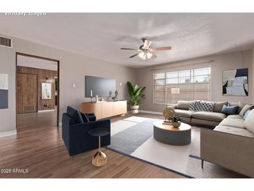 Bright living room boasts a ceiling fan, recessed lighting, large window and wood look floors at 3823 W Berridge Ln, Phoenix, AZ 85019