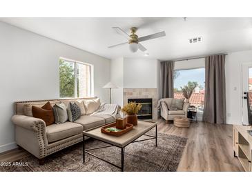 Inviting living room featuring a fireplace, ceiling fan, and cozy seating area at 10080 E Mountainview Lake Dr # 327, Scottsdale, AZ 85258