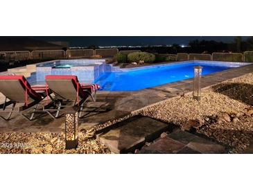 Inviting pool and spa with elegant tile work, illuminated by designer lighting in a well landscaped backyard overlooking the city lights at 11986 N 134Th Pl, Scottsdale, AZ 85259