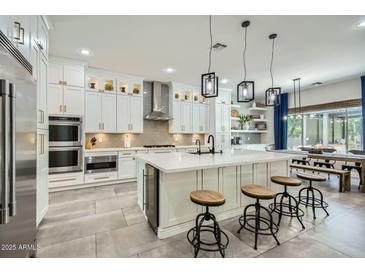 Open-concept kitchen featuring white cabinetry, a large center island, and stainless steel appliances at 1890 E Sagittarius Pl, Chandler, AZ 85249
