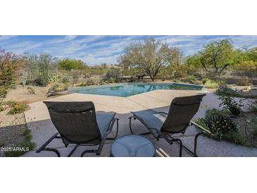Relaxing poolside view with lounge chairs, sparkling blue water, and lush desert landscaping at 7486 E Bajada Rd, Scottsdale, AZ 85266