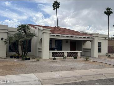Charming single-story home with a terracotta roof, front porch and desert landscaping at 8343 E San Ricardo Dr, Scottsdale, AZ 85258