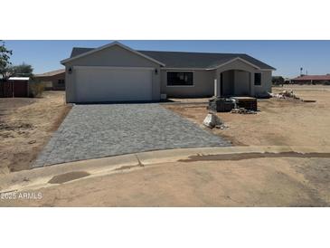 Single-story home featuring a gray paver driveway and an attached two-car garage at 9280 W Wenden Dr, Arizona City, AZ 85123