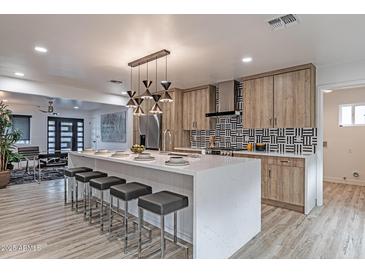 Modern kitchen with white quartz island, sleek lighting, wood cabinets, and black and white backsplash at 1539 W Puget Ave, Phoenix, AZ 85021