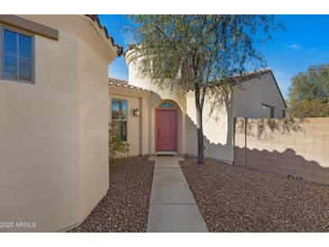 Charming single-story home features a landscaped front yard, a terracotta roof and a pink entrance door at 29798 N 121St Dr, Peoria, AZ 85383