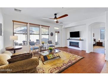 Open-concept living room with a fireplace and a view into the backyard at 29798 N 121St Dr, Peoria, AZ 85383