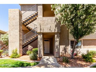 Multi-level condo complex featuring stucco siding, metal stairs, and mature landscaping near the front entrance at 3830 E Lakewood Pkwy # 1057, Phoenix, AZ 85048