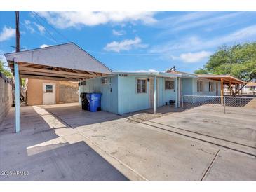 Exterior shows a blue house with covered parking, a large concrete driveway, and a chain link fence at 6447 W Piccadilly Rd, Phoenix, AZ 85033