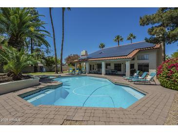 Enjoy this large backyard pool surrounded by lounge chairs, palm trees, and lush landscaping at 12537 N 76Th Pl, Scottsdale, AZ 85260