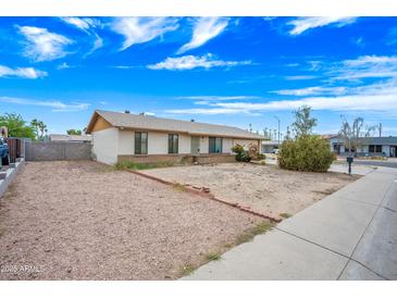 Single story home featuring desert landscaping, a brick accent, and a light colored exterior at 1827 W Bluefield Ave, Phoenix, AZ 85023