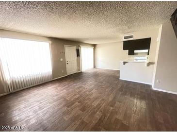 Spacious living room featuring wood floors, large windows, and a convenient breakfast bar to the kitchen at 2133 W Turney Ave # C88, Phoenix, AZ 85015