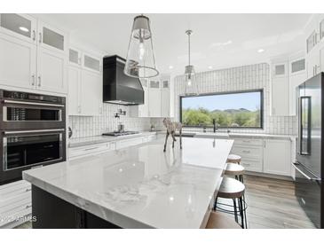 Bright, modern kitchen with white cabinets, marble counters, stainless steel appliances, and island seating at 38953 N 57Th Pl, Cave Creek, AZ 85331
