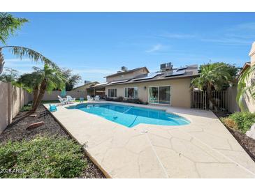 Relaxing backyard featuring a refreshing pool, lush landscaping, and comfortable seating under a clear blue sky at 6101 W Grandview Rd, Glendale, AZ 85306