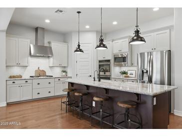 Modern kitchen featuring a large island, stainless steel appliances, white cabinets, and hardwood floors at 10154 E Bergeron Ave, Mesa, AZ 85212
