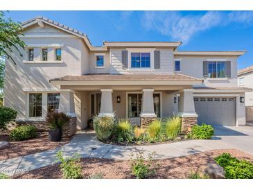 Inviting two-story home featuring a covered porch with stone accents and a well-manicured front yard at 18868 E Mockingbird Dr, Queen Creek, AZ 85142