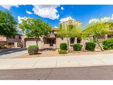 Charming desert home featuring a landscaped yard, attached garage, and a welcoming entrance with a wrought-iron gate at 26853 N 89Th Dr, Peoria, AZ 85383