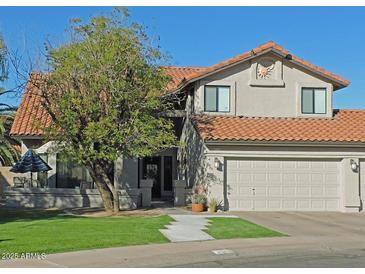 Charming two-story home with a well-manicured lawn, mature tree, and a clay tile roof at 1010 N Osprey Ct, Gilbert, AZ 85234