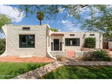 Charming home featuring stucco exterior, a red tile roof detail, black trimmed windows, and well-manicured front lawn at 356 W Roma Ave, Phoenix, AZ 85013
