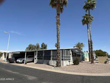 Charming mobile home featuring a covered parking area and mature palm trees at 9501 E Broadway Rd # 21, Mesa, AZ 85208