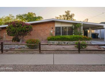 Charming brick home with colorful landscaping, wood fence, and covered carport at 4620 N 38Th Dr, Phoenix, AZ 85019