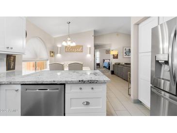 Open-concept kitchen with stone countertops, breakfast bar and stainless steel dishwasher at 8948 W Fargo Dr, Peoria, AZ 85382
