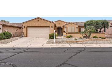 Inviting single-story home with desert landscaping, mature trees, and a well-kept lawn at 17009 W Eureka Springs Dr, Surprise, AZ 85387