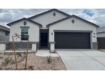 Charming single-story home featuring a stucco facade, dark gray accents, a two-car garage, and a low-maintenance front yard at 25479 W Graham Trl, Buckeye, AZ 85326
